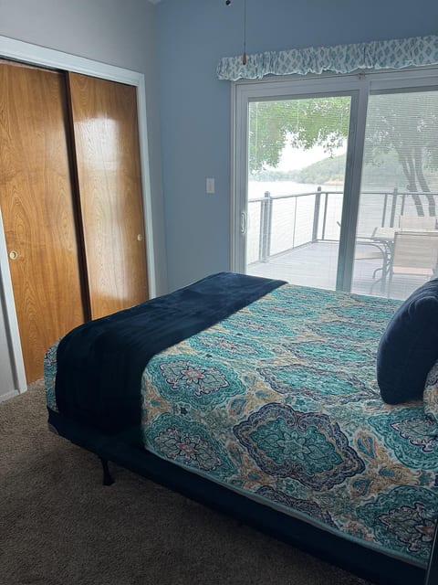 Lake-view bedroom with deck access, plush bedding, and natural light.