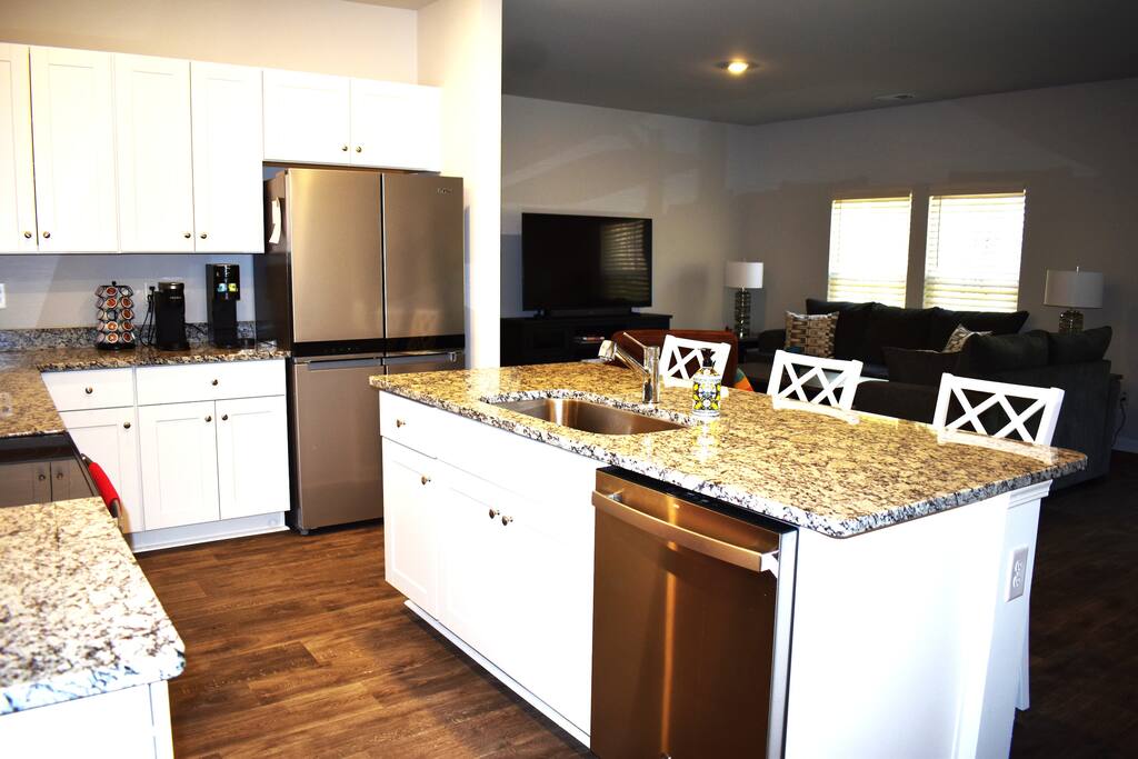 Modern kitchen with granite counters, stainless steel appliances, and island seating — fully stocked for home-cooked meals and perfect for entertaining during your stay.
