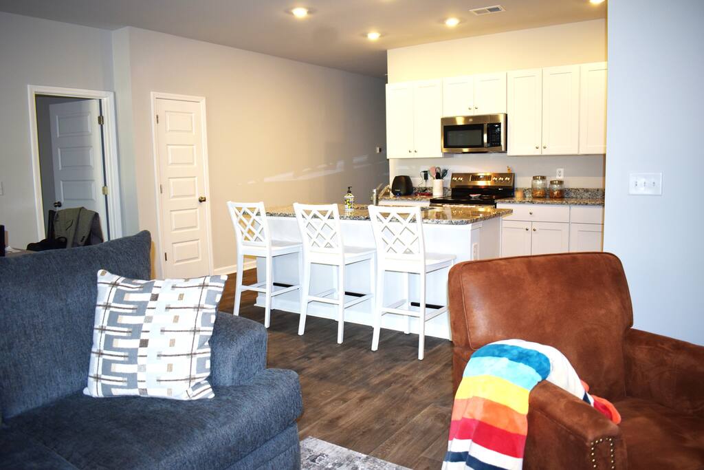 Modern kitchen with granite counters, stainless steel appliances, and island seating — fully stocked for home-cooked meals and perfect for entertaining during your stay.