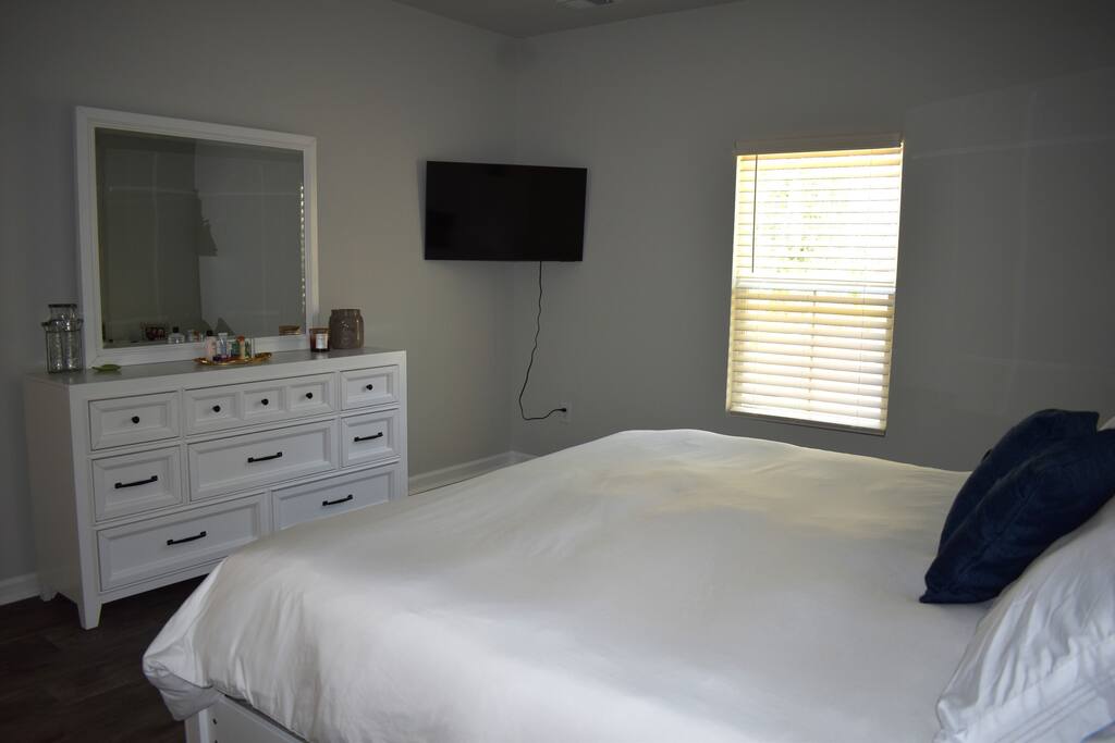Spacious primary bedroom with a plush king bed, blackout shades, smart TV, and cozy lighting — a relaxing retreat perfect for winding down after a day of exploring.