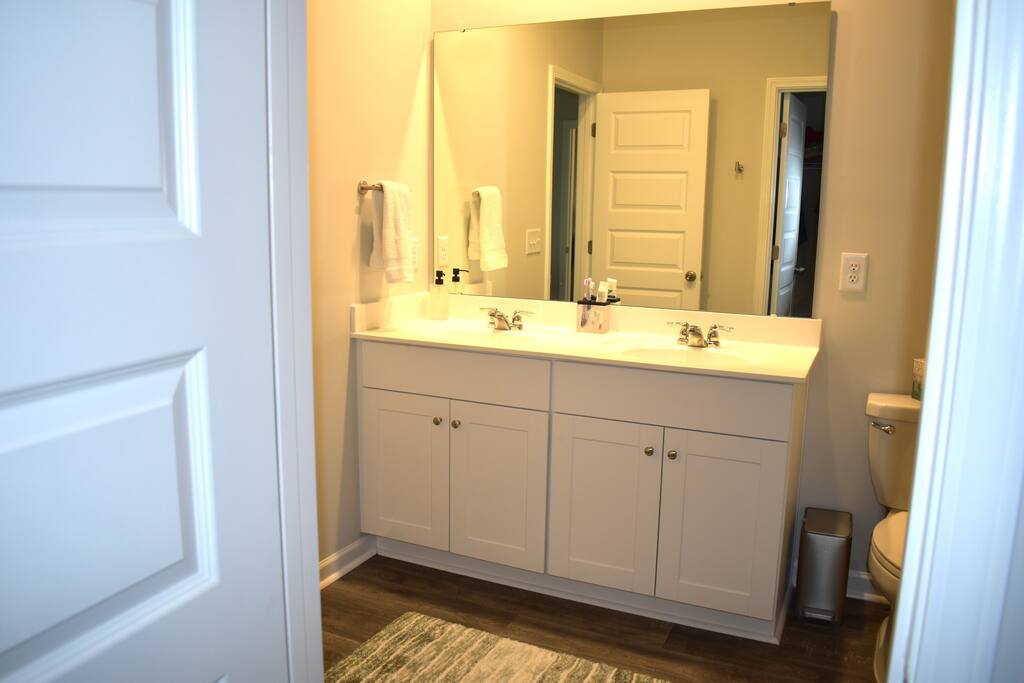 Spacious, sparkling-clean bathroom featuring dual sinks, a full tub/shower combo, and plush bath rugs. Well-stocked with towels and essentials to make your stay as comfortable as home!