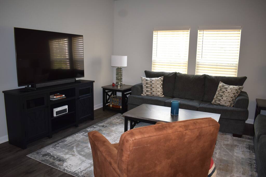 Modern living room with a large smart TV, plush seating, and stylish decor — perfect for streaming your favorite shows, relaxing with family, or enjoying a cozy night in.