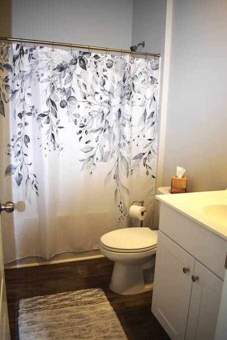 Cozy and clean bathroom featuring a stylish floral shower curtain, soft rug, and essentials stocked for your stay. A peaceful, private space perfect for unwinding after a day of adventure!