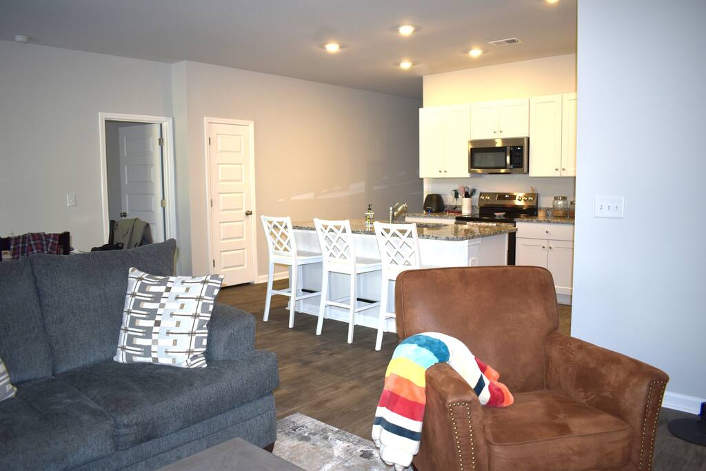 Bright, modern kitchen with granite countertops, stainless steel appliances, and a large island with seating — perfect for cooking, gathering, and casual dining.