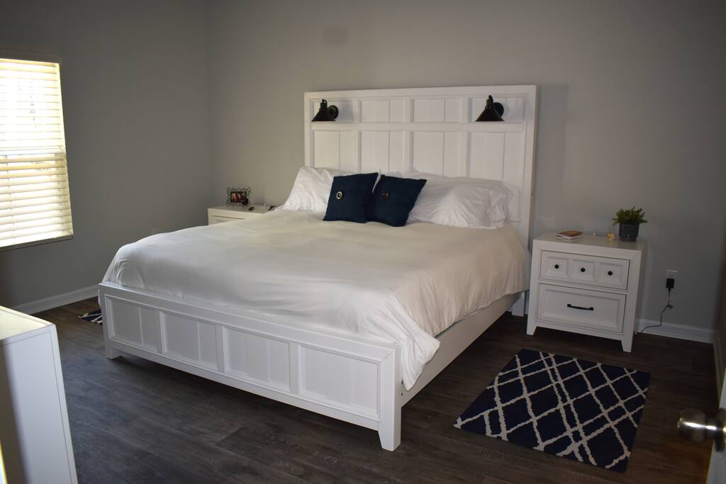 Spacious primary bedroom with a plush king bed, blackout shades, smart TV, and cozy lighting — a relaxing retreat perfect for winding down after a day of exploring.
