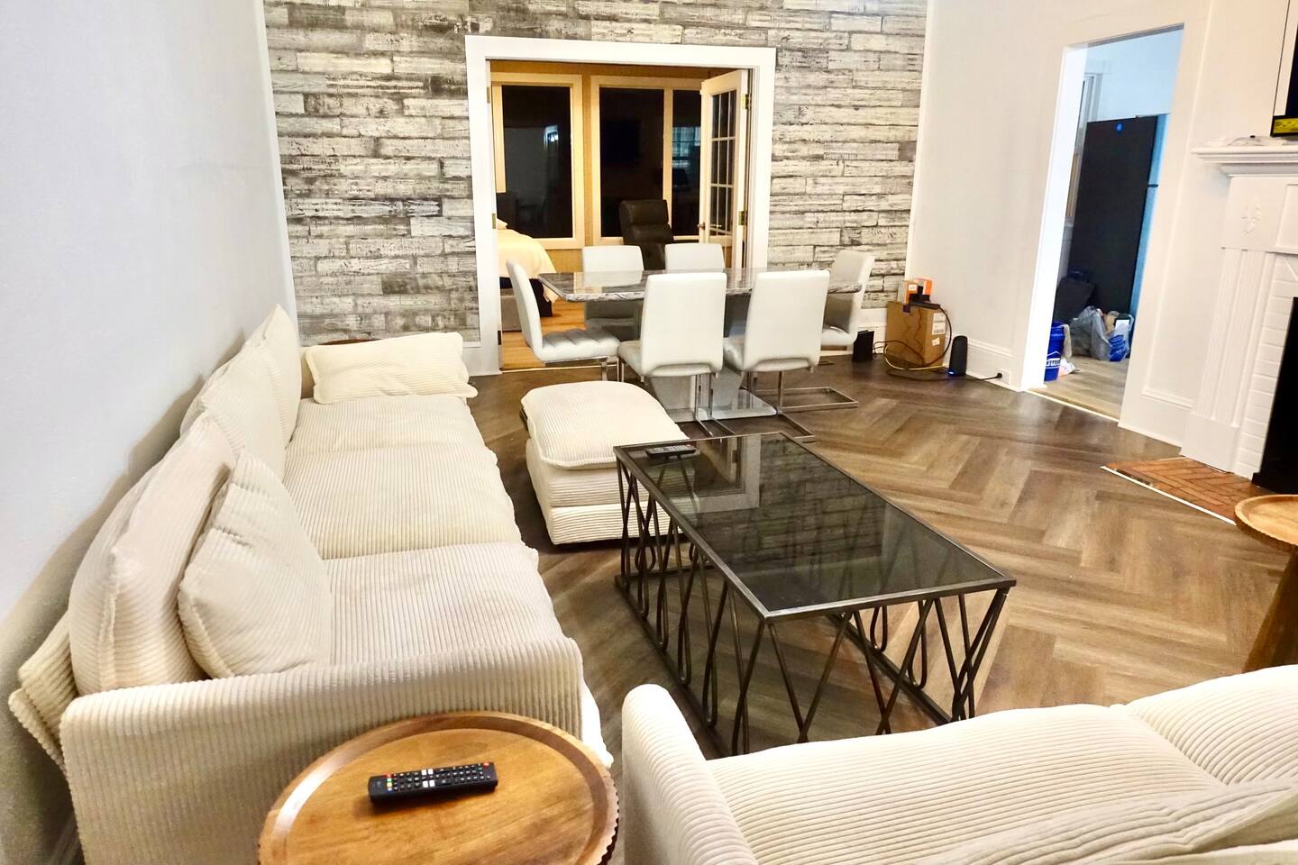 Comfortable seating area with large sectional, sleek glass coffee table, and view into the modern dining space—great for lounging and socializing.