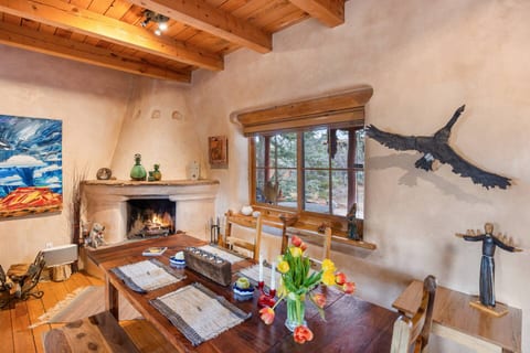 Charming dining area with kiva fireplace, rustic table, and nature views—perfect for cozy meals.