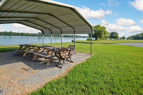 Covered lakeside pavilion with picnic tables and firewood—perfect for shaded outdoor meals.