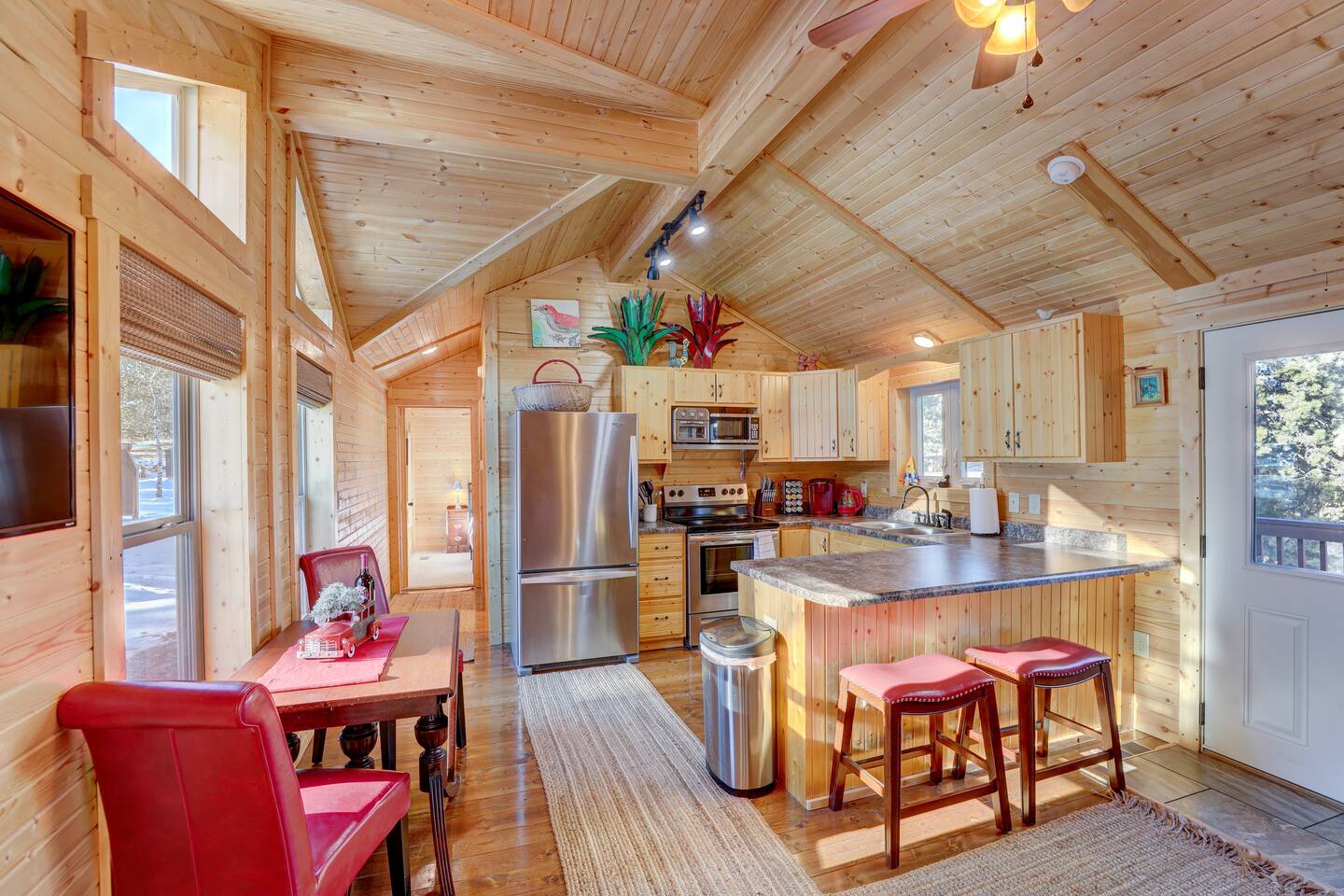 Bright and welcoming kitchen with rustic charm, colorful decor, and easy access to the bedrooms through the hallway.
