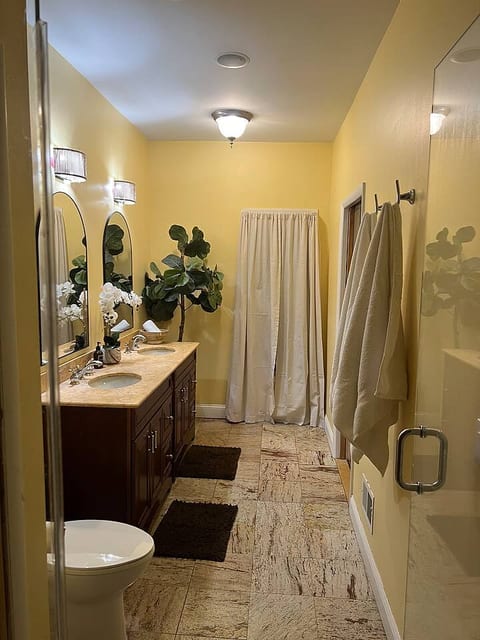 Indulge in a tranquil retreat. This spacious bathroom features a double vanity and a glass-enclosed shower, offering you a serene space to unwind and prepare for your day. Enjoy the warm, inviting tones and thoughtful decor.
