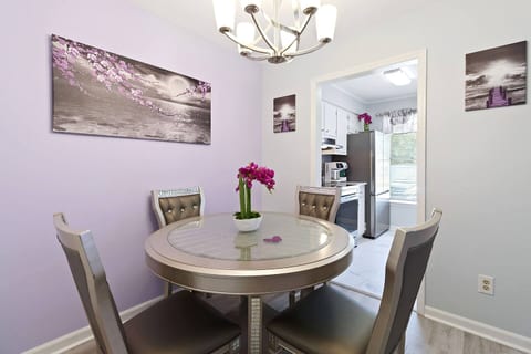 The modern, round glass table and comfortable chairs offer a stylish setting for your stay. You will find beautiful art, a chandelier, and a view into the kitchen, creating a bright and inviting space.