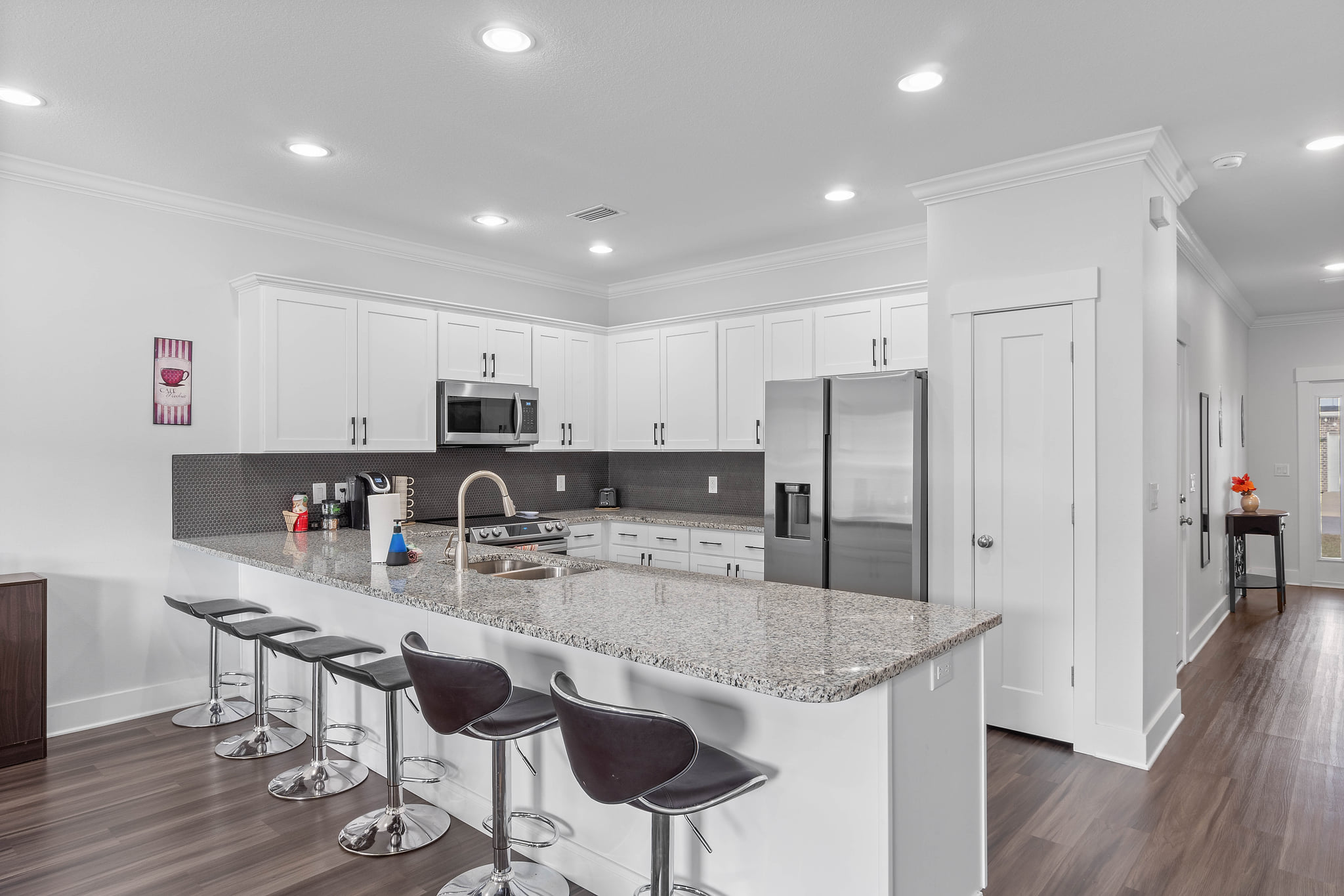 Sleek chef’s kitchen with big island, seating for five, SS appliances.