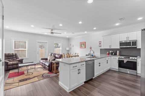Bright open-plan kitchen with island, stainless appliances, cozy lounge