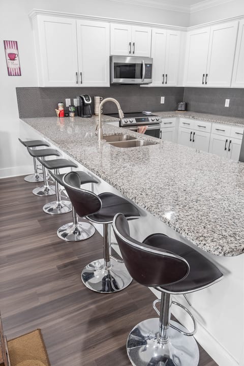 Sleek chef’s kitchen with long granite island, seating for five and coffee bar.