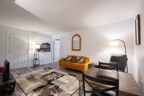 Golden sofa with bold pillows and a woven mirror add a cheerful, modern touch that blends comfort with style.