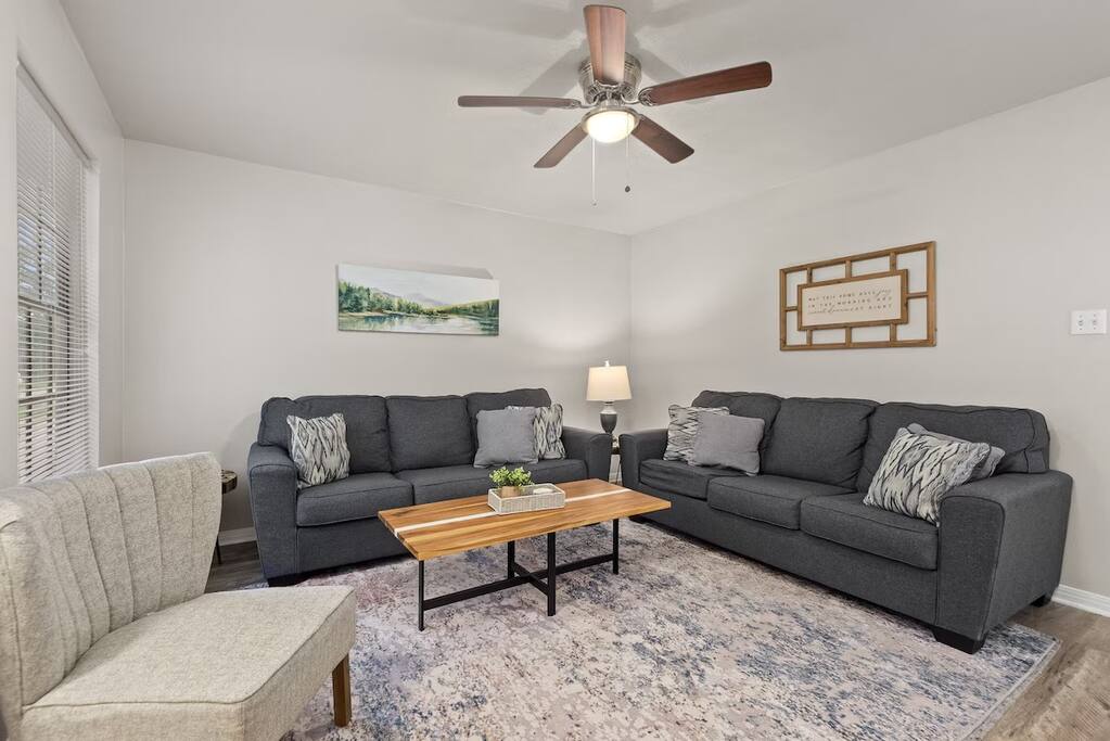 Bright living room with comfortable seating, ceiling fan, and cozy décor, perfect for relaxing.
