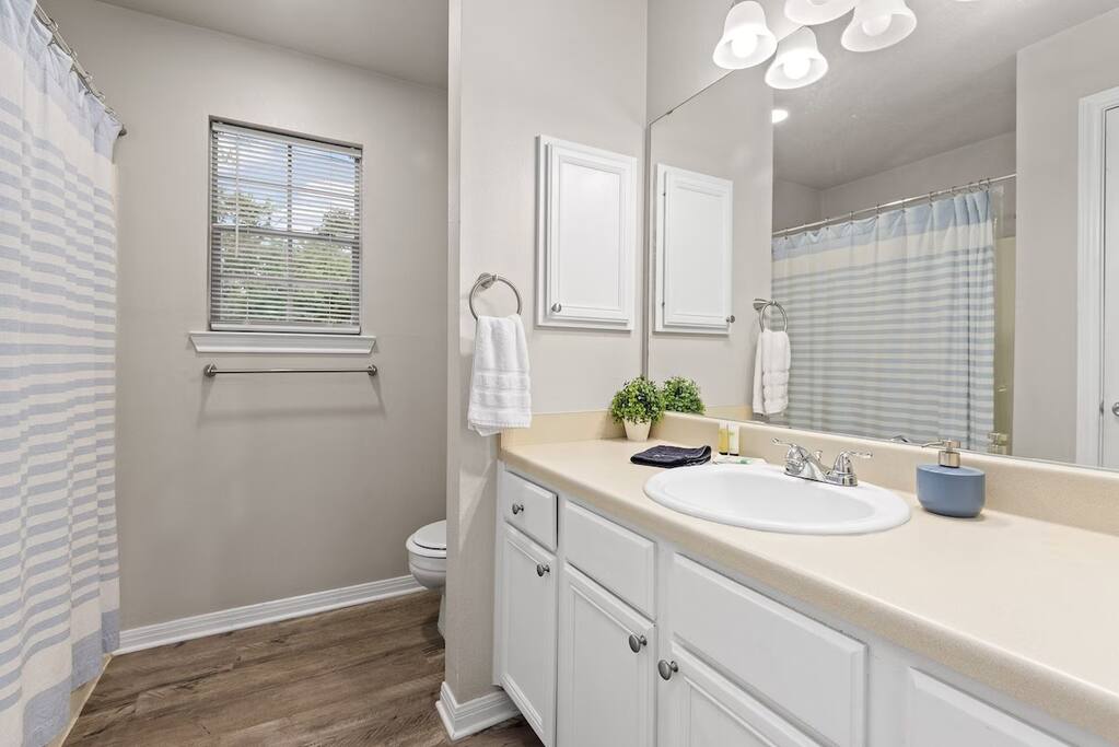Bathroom with bright lighting, mirror, and fresh towels.