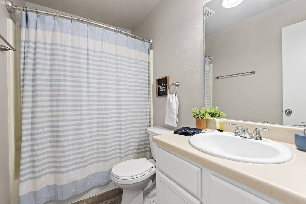 Fresh and bright bathroom with shower/tub combo, vanity, and guest essentials.