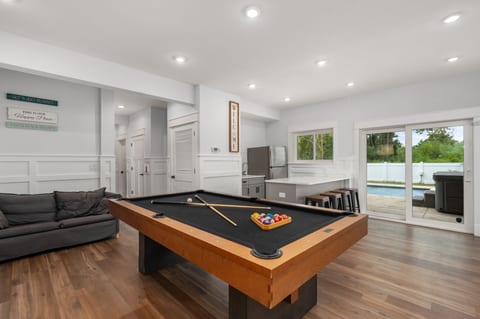 Enjoy this chic game room with a sleek pool table, cozy sofa, and wet bar. Sliding doors open to a pool view, blending indoor fun with outdoor bliss—great for family time.