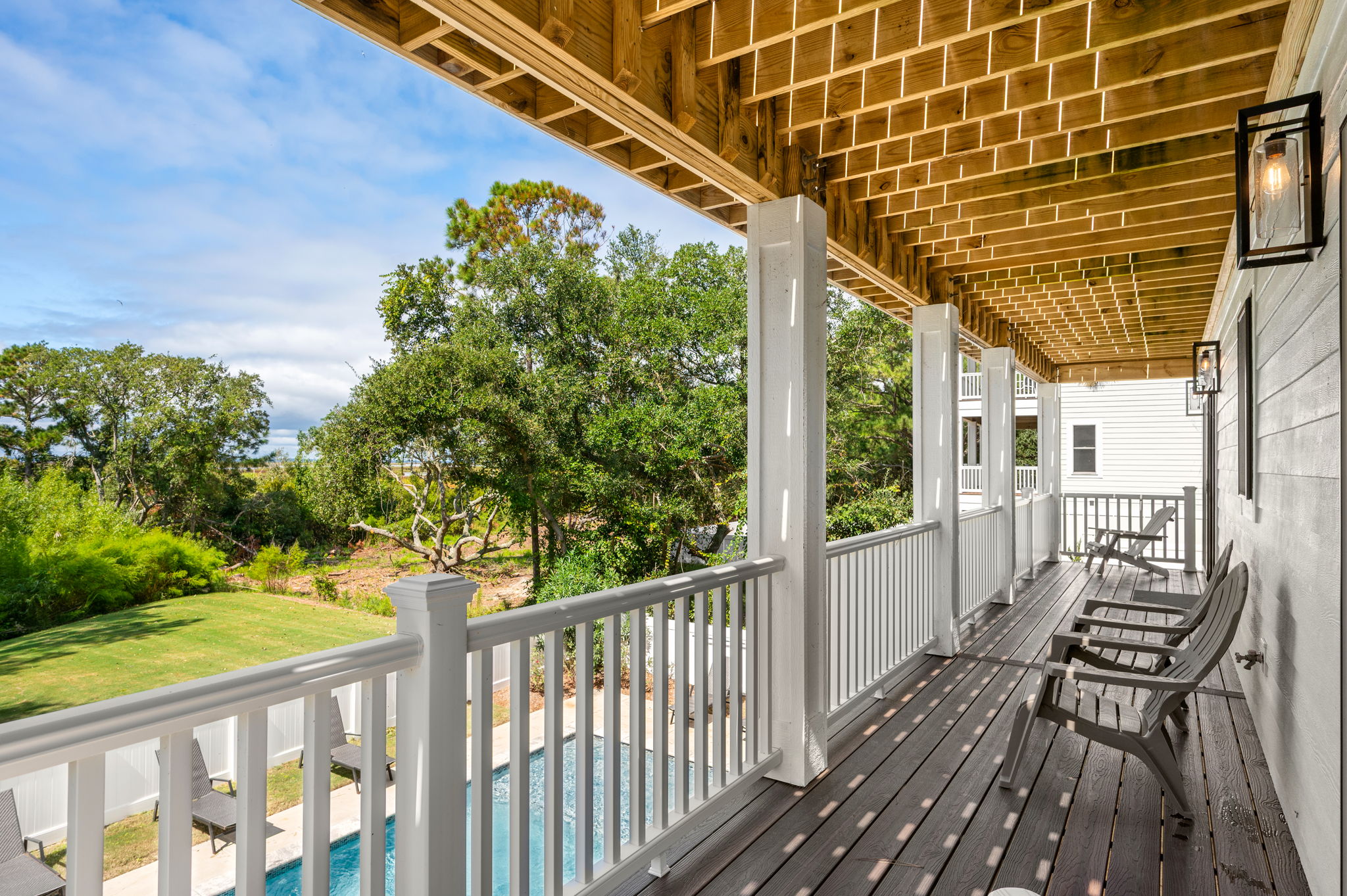 Relax on the shaded mid-level deck, which offers a perfect, elevated vantage point overlooking the private pool and the surrounding outdoor area.