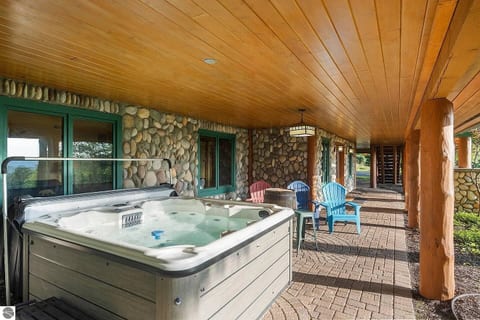 Relax in the bubbling hot tub on the covered patio surrounded by rustic stonework and peaceful forest views. Perfect for unwinding after a day of adventure, rain or shine, in total comfort.