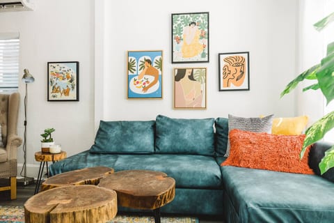 Vibrant gallery wall meets comfy sofa—this cozy corner is perfect for lounging, reading, or sharing a glass of wine in a bold, art-inspired setting.