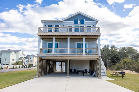 Welcome to your coastal retreat! Out front, enjoy a wide driveway and carport for easy parking. The fun begins with a ping pong table, park-style grill, and picnic table—perfect for cookouts, games, and family gatherings.