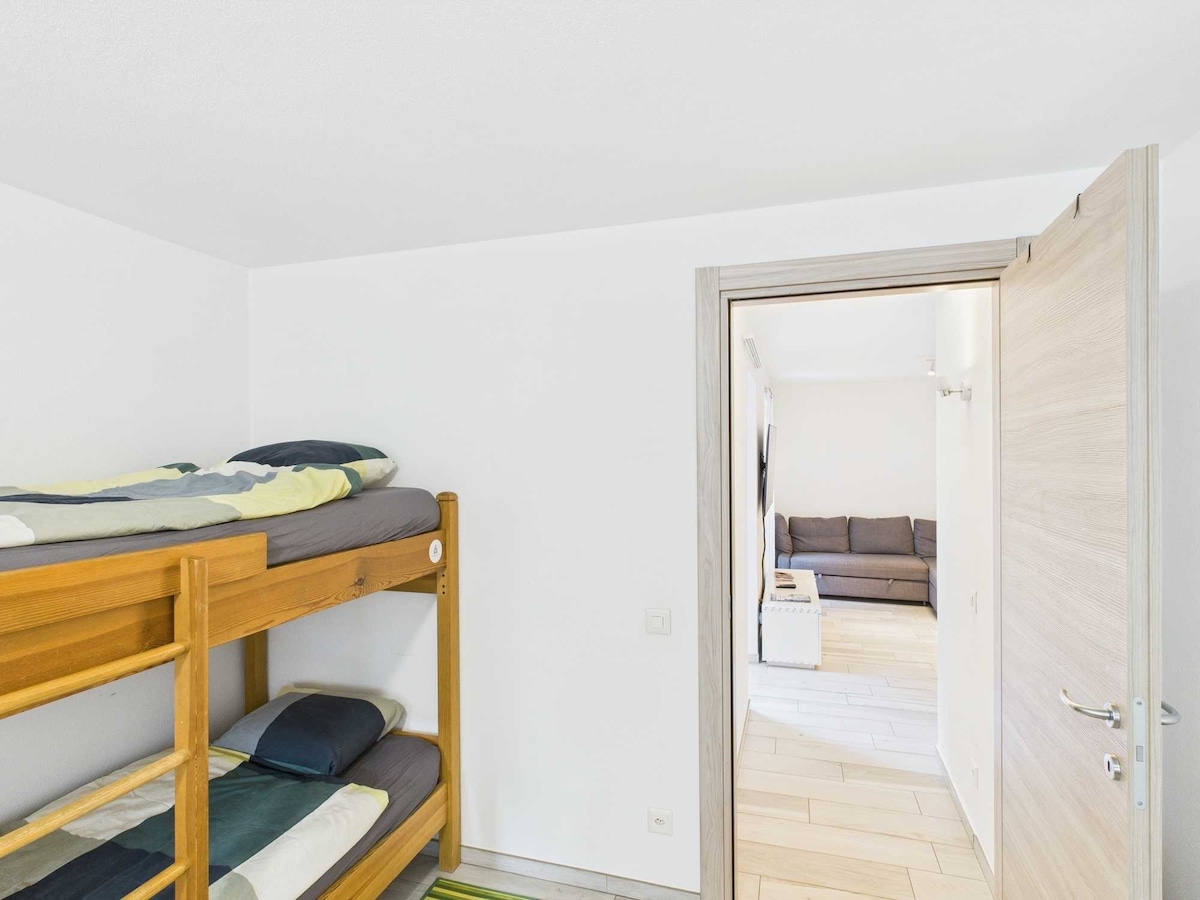 Dalla camera, si apre una vista sul soggiorno, luminoso e accogliente. L'open space amplifica la sensazione di spazio, creando un ambiente ideale per rilassarsi o socializzare, con arredi moderni che aggiungono comfort e stile all'atmosfera.