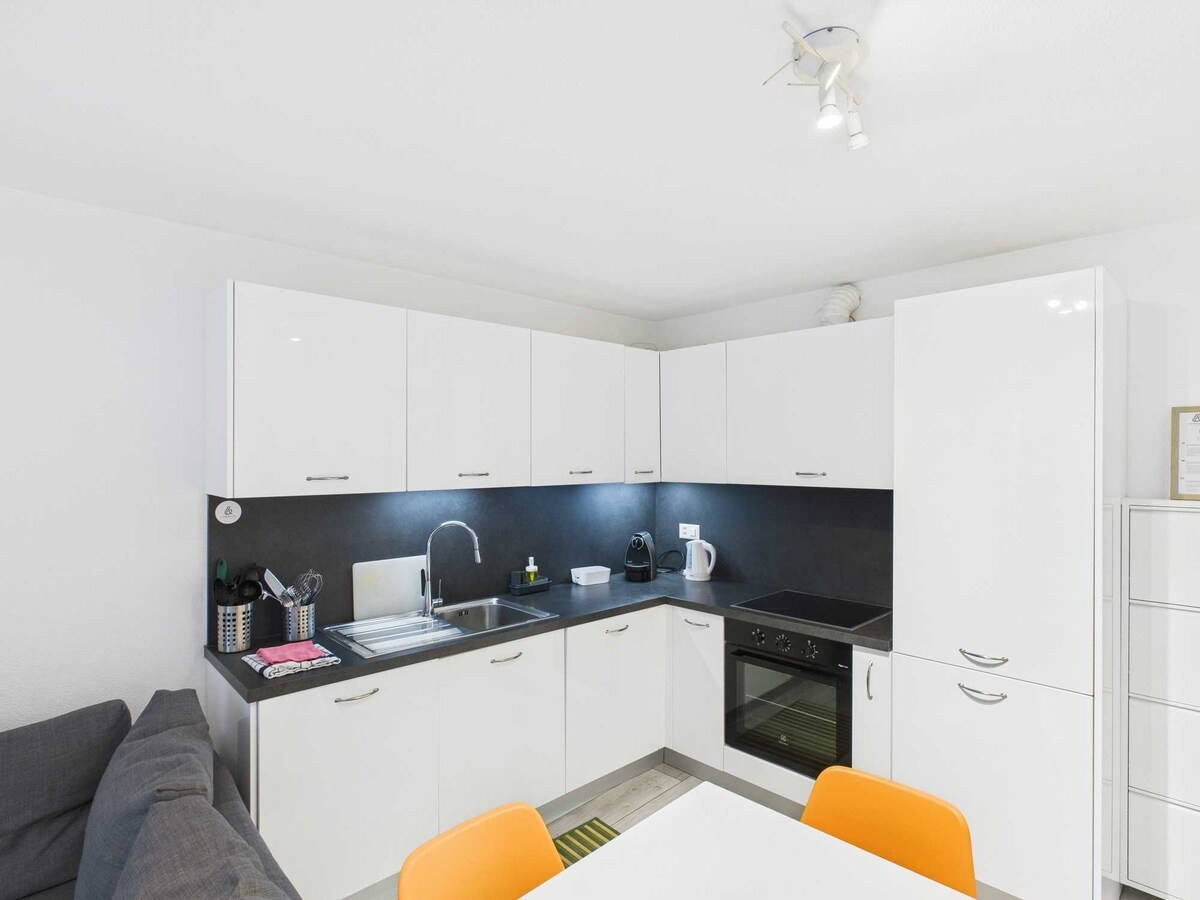 Una zona pranzo moderna con cucina ad angolo, completa di elettrodomestici, tra cui lavastoviglie e lavasciuga. L’ambiente funzionale e ben organizzato è ideale per preparare e gustare i pasti in modo pratico e confortevole.