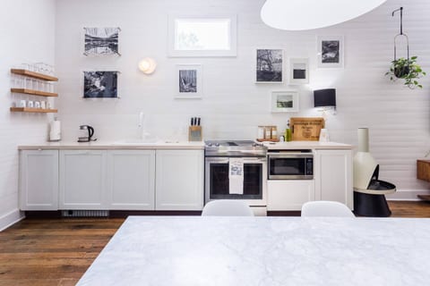 Its bright, open kitchen anchors the space, featuring a sleek downdraft oven that preserves the room’s airy sightlines and a whisper-quiet microwave seamlessly integrated into custom cabinetry.
