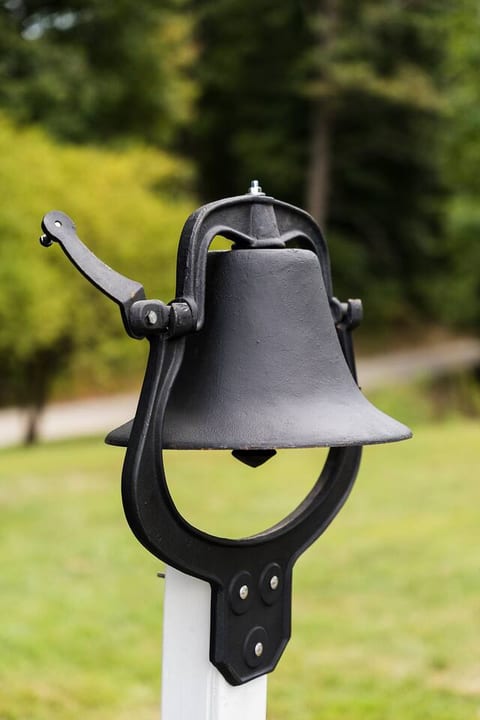 A cast iron bell at the entry adds a charming, historic touch, welcoming guests to the schoolhouse with a nod to its heritage and timeless character.