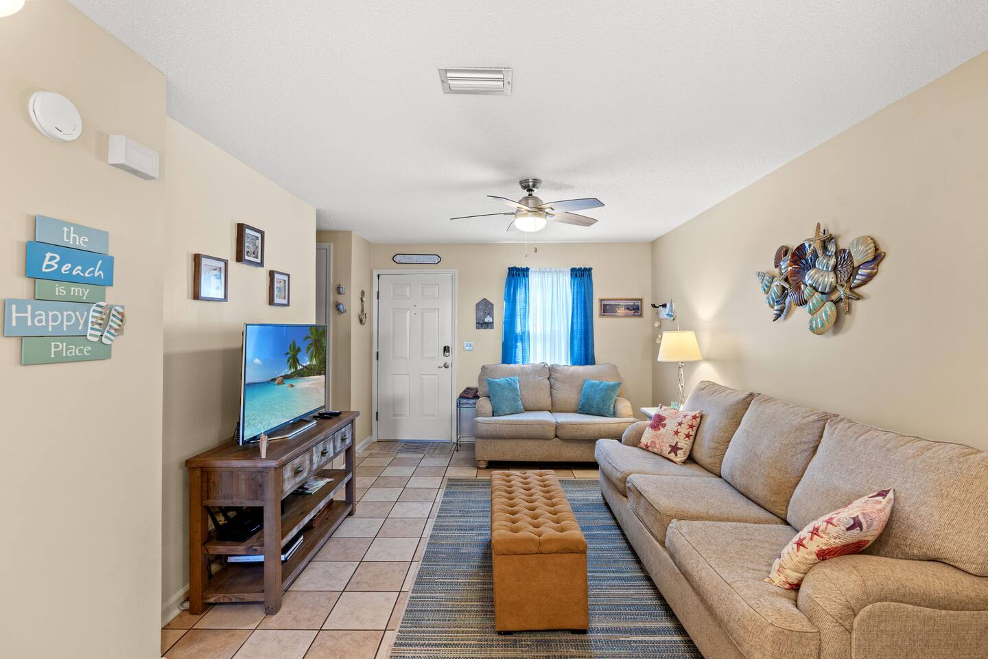 This inviting living area features cozy seating, and a flat-screen TV,  perfect for relaxing after a day at the beach or enjoying movie nights with family and friends.