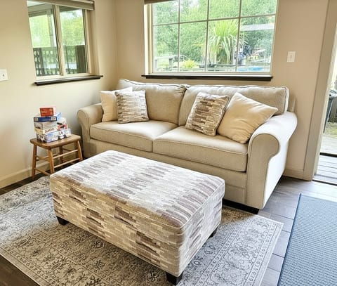 Bright, cozy lounge with plush sofa, ottoman coffee table, and board games.