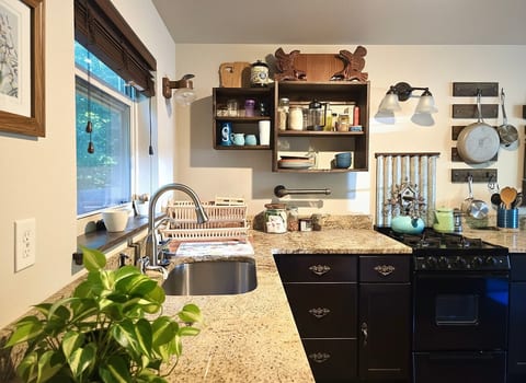 Cozy kitchen with granite counters, gas stove & open shelving