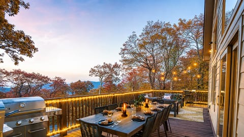 Twilight on the deck — mountains fading in the distance, wine glasses catching the glow of string lights, dinner sizzling on the grill. This is what gathering should feel like