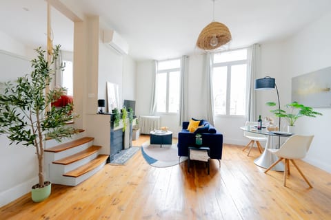 Sunlit lounge with hardwood floors, AC, and a chic dining nook.