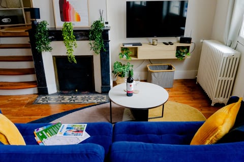 Chic lounge with plush sofa, wall TV, plants, and wine-ready table