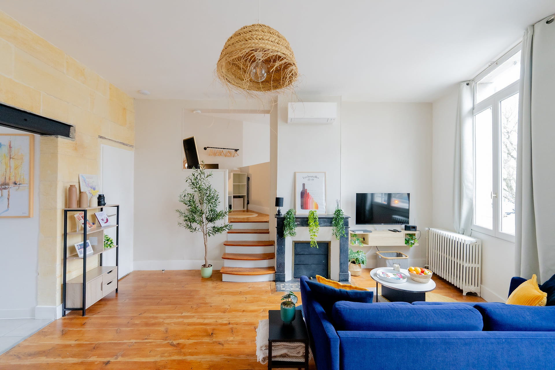 Sunny living room with chic décor, blue sofa, TV, and cozy fireplace