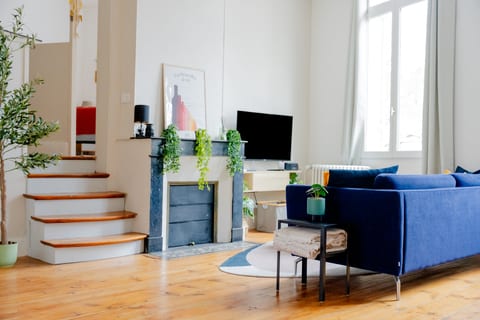 Sunny living room with blue sofa, fireplace decor, and big windows