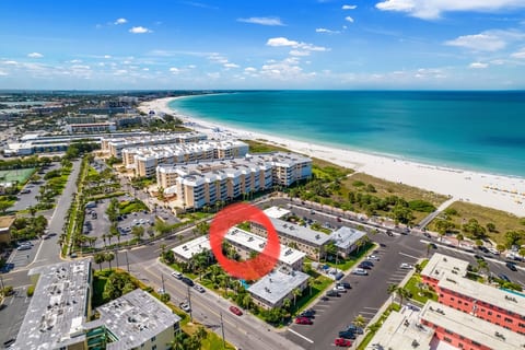 Cross the parking spaces and dunes... to have your toes in the sand. Famous beach bars /restaurants to the left of the peach condos on the left.