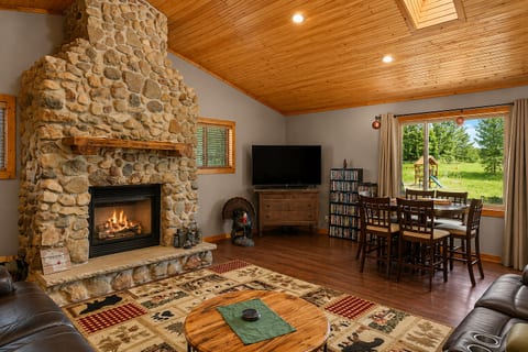 Cozy cabin-style living room with stone fireplace and scenic dining nook