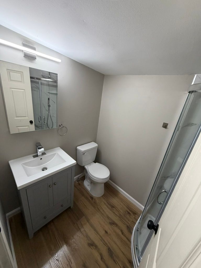 Updated modern bathroom with glass shower and stylish wood-look flooring