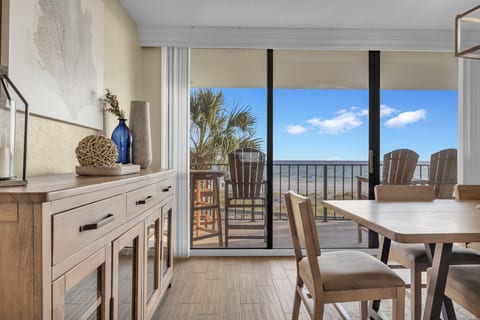 Charming coastal dining nook accented with warm wood tones and ocean-view backdrop