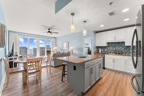 Inviting open-floor plan showcasing a modern kitchen, island seating, and views of the gulf beyond.