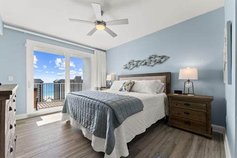 Spacious master suite with king bed, coastal décor, and direct balcony access overlooking the beach.