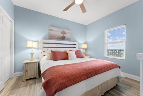 Inviting guest bedroom with a king bed, warm coral tones, and plenty of natural light.