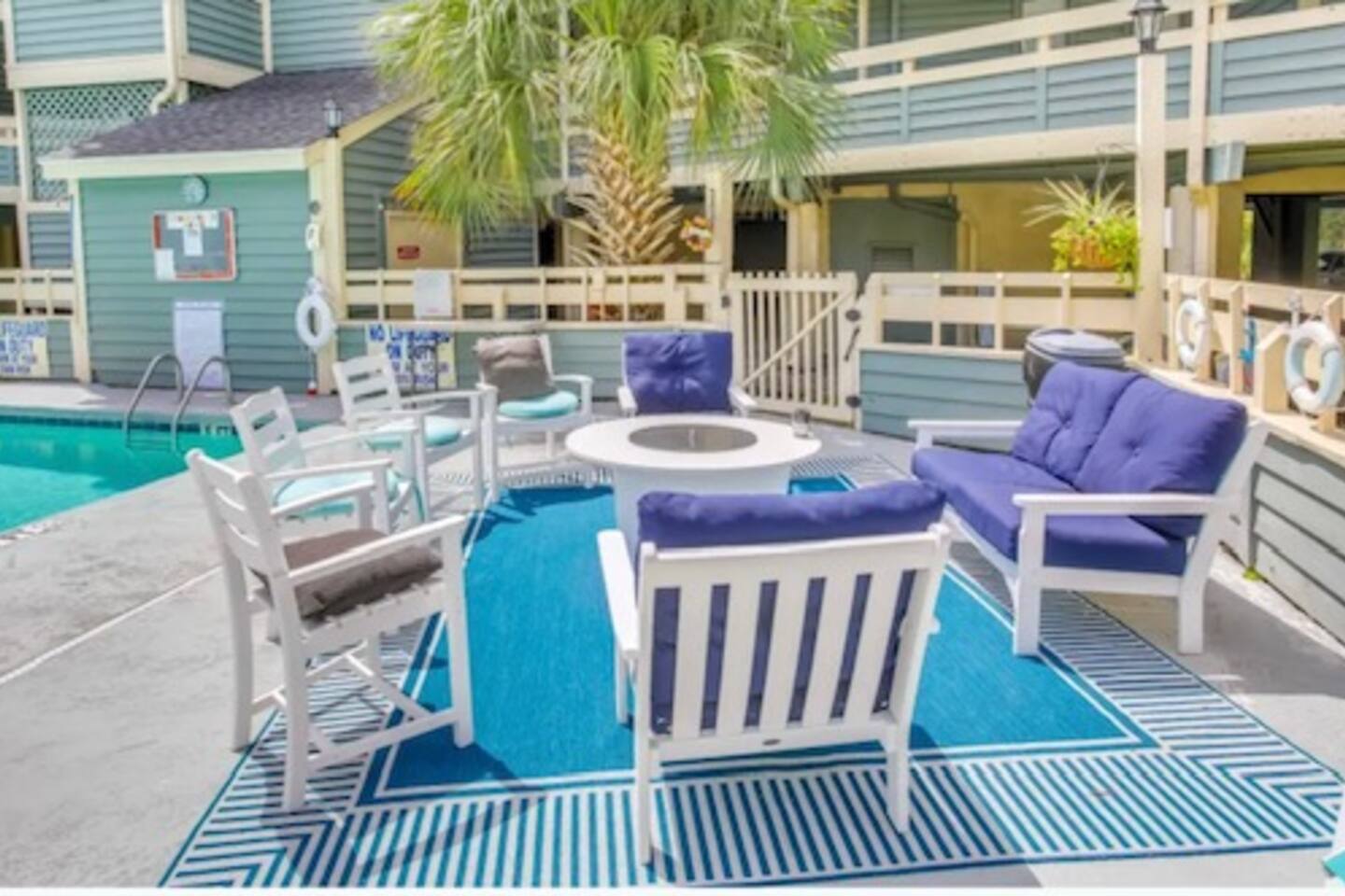 Gather around the cozy poolside fire pit and enjoy laid-back conversations under the palm trees in this inviting outdoor lounge.