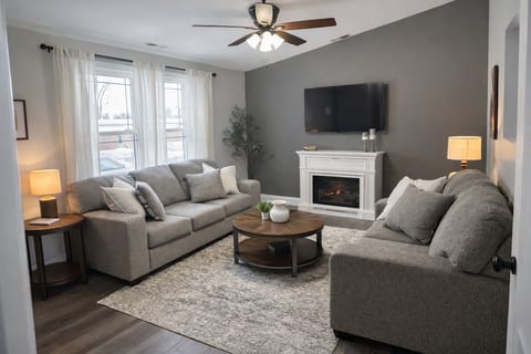 Living room with sofa seating for 5. Wall mounted TV with Roku Guest Mode, electric fireplace.