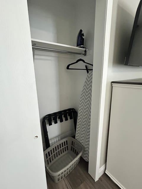 Closet offers hangers, ironing board, iron and plenty of space for storage.