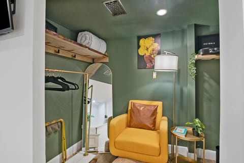 The Green Hideaway room highlights the lounge chair, mirror, lamps, and hangers — thoughtful touches that keep the space comfortable and easy to settle into.